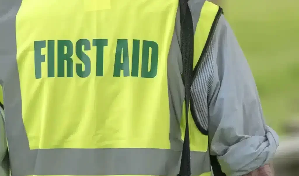 Male first responder wearing high-visibility first aid jacket carrying emergency medical kit
